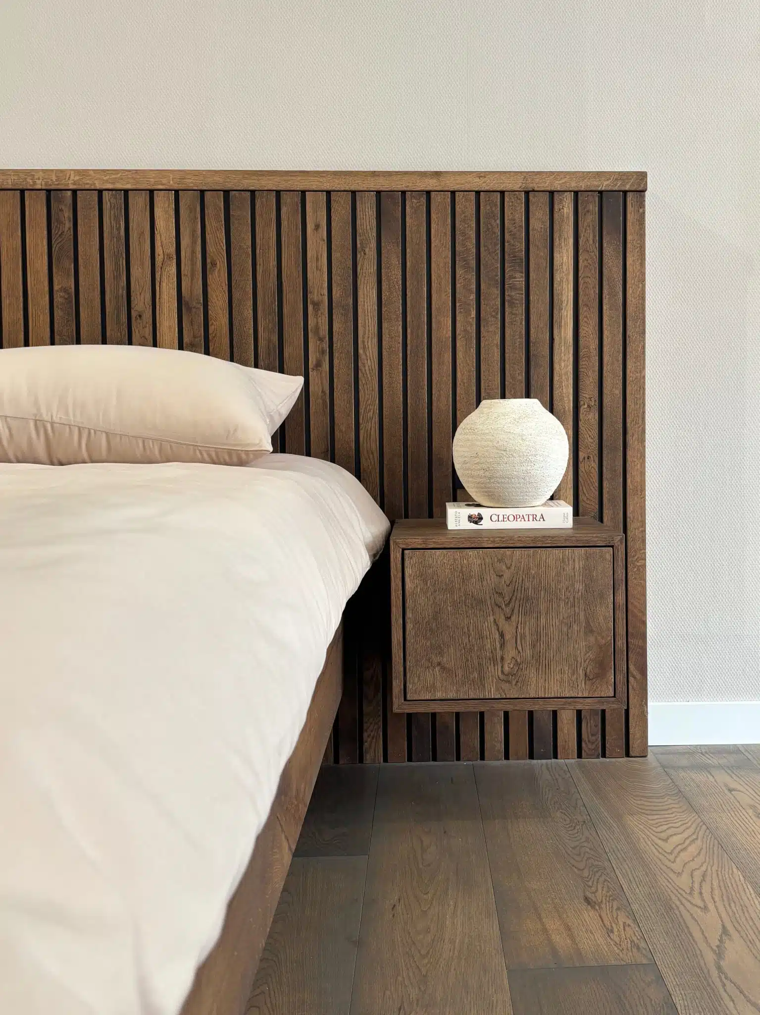 Detail van een massief eiken bed met nachtkastje